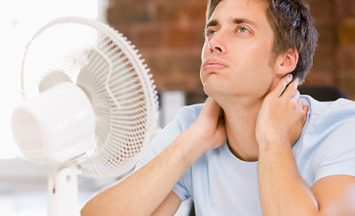 man suffering in the heat with fan