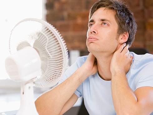 man suffering in the heat with fan