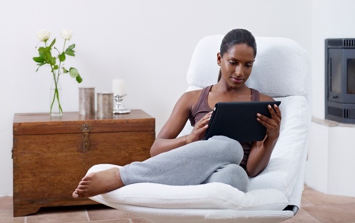 woman-relaxing-on-armchair-in-home-reading-online