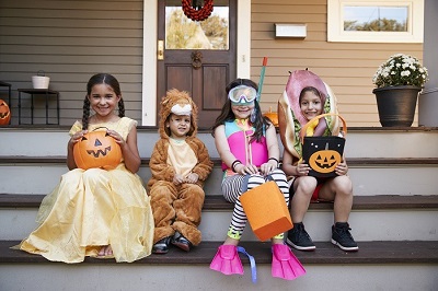 4 kids on a front porch in Halloween costumes